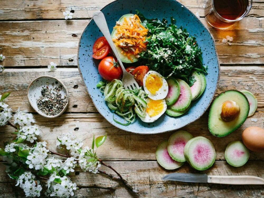 A balanced and energetic healthy food, which consists of vegetables, fruits, and egg slices. 